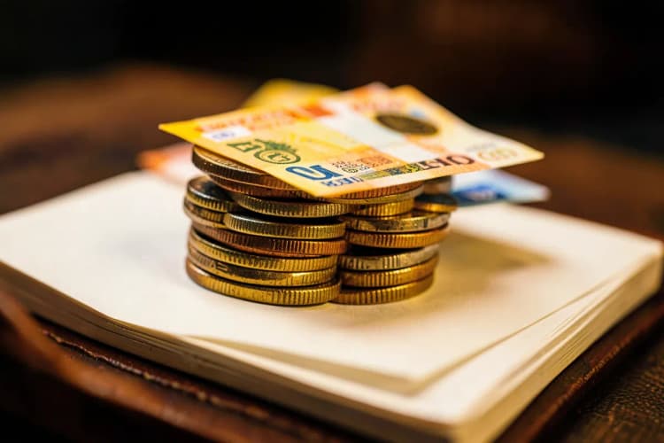 Moedas e notas de dinheiro empilhadas em cima de um livro aberto